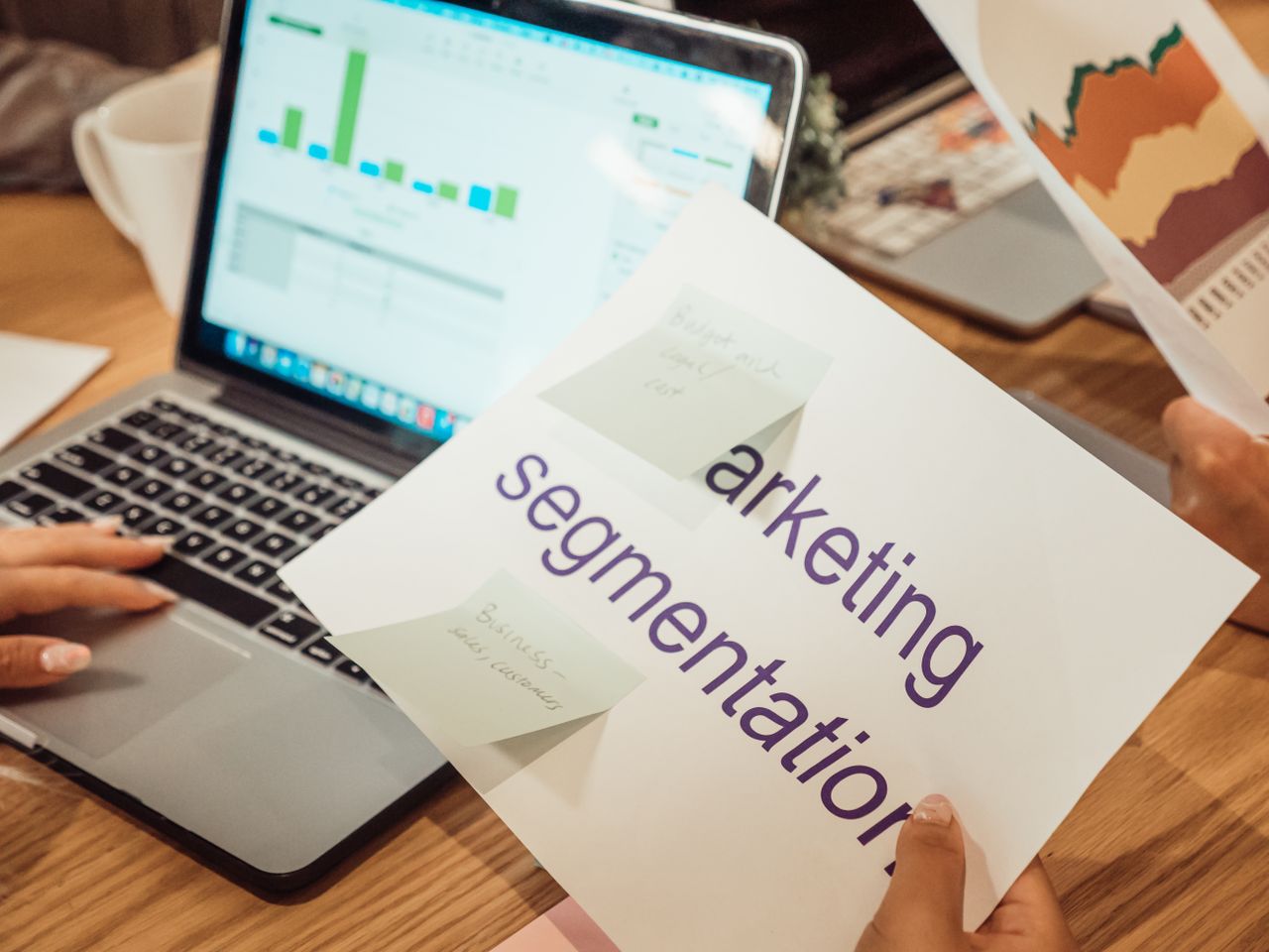 home-hero-bg A contemporary workspace where hands review marketing data on a laptop alongside paper documents.